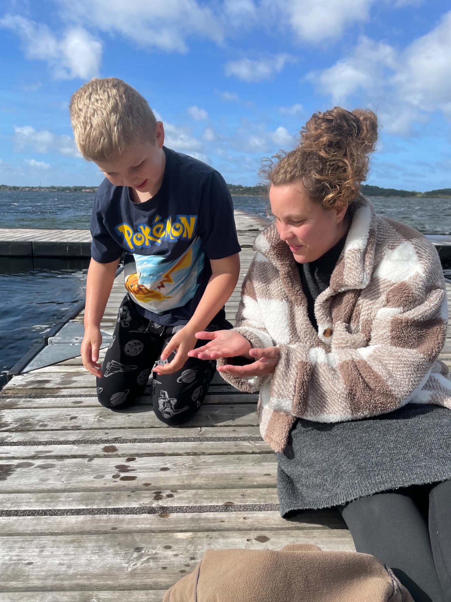 Et barn og en voksen ser nærmere på et fund ved badebroen