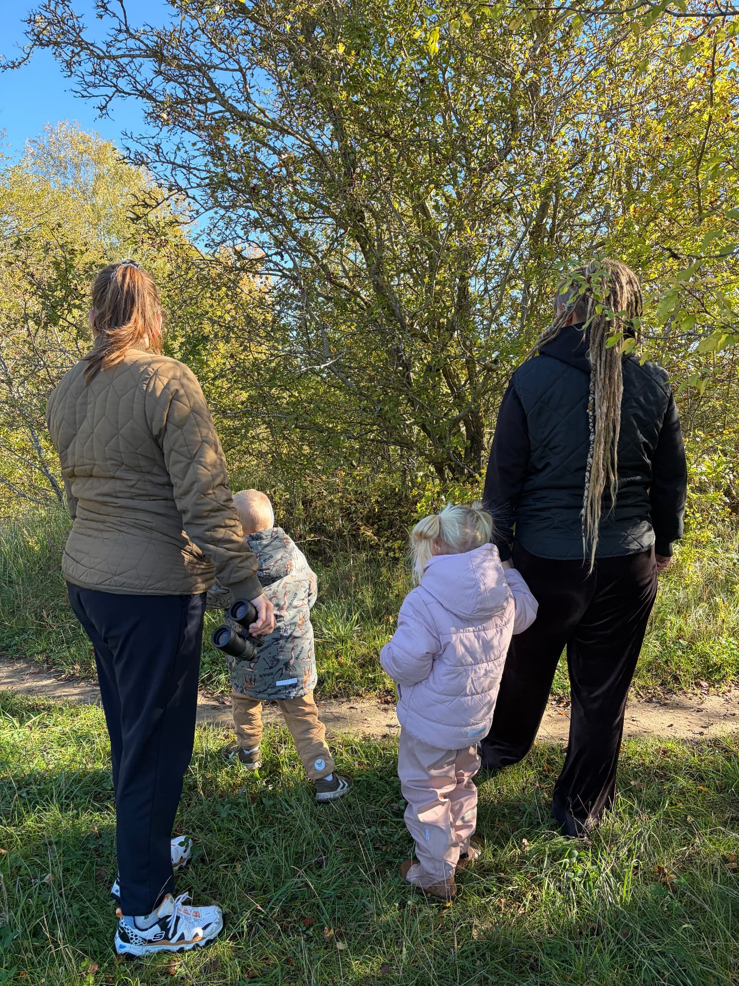To voksne og to børn kigger nærmere, med kikkert klar