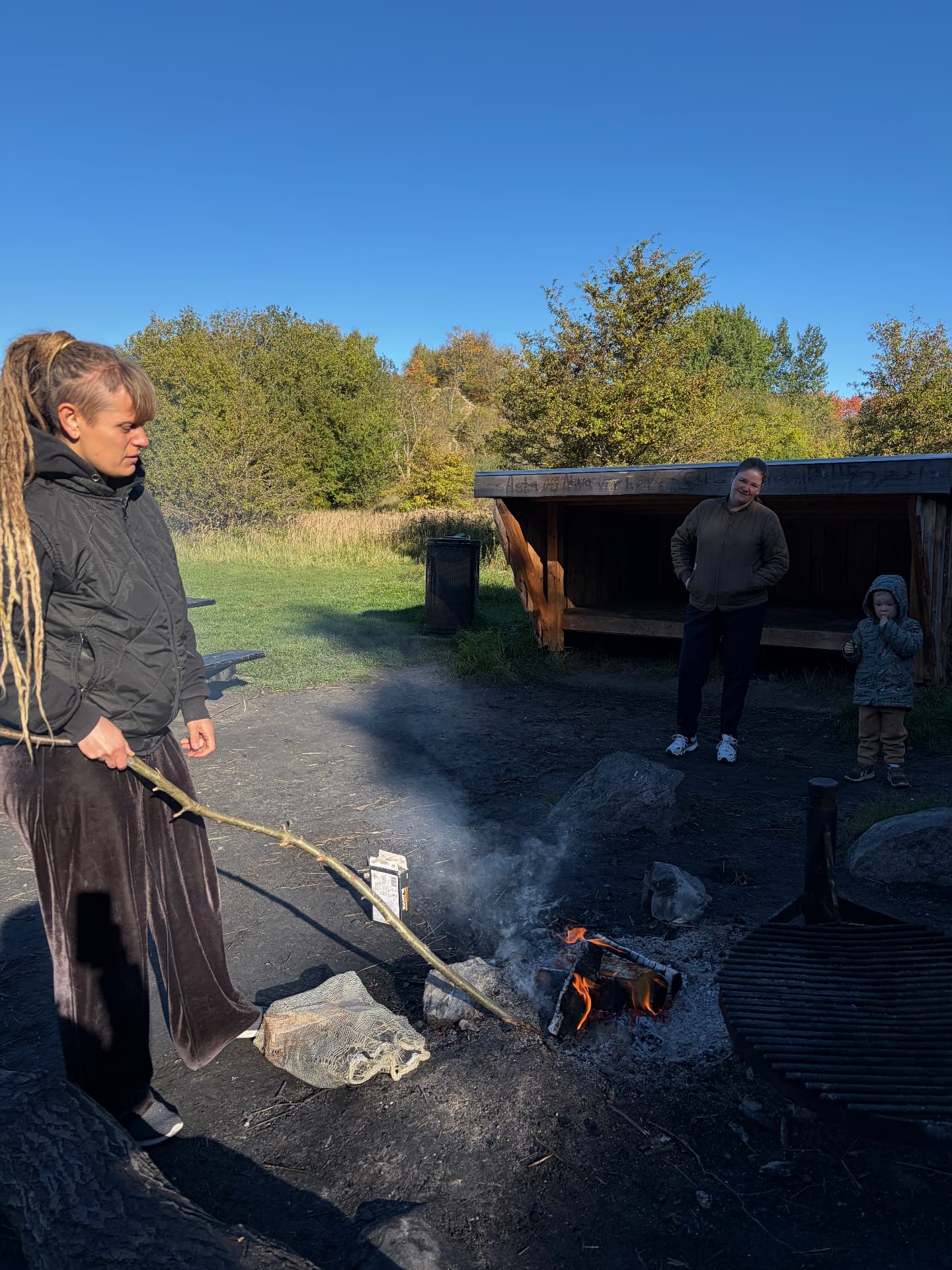 En voksen passer bålet med en lang pind